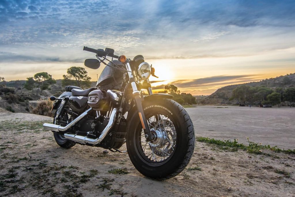 A Harley 48 motorcycle parked on a road, with a captivating sunset as the backdrop.